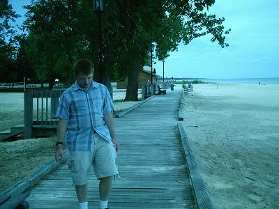 Man walking down a  pathway by the beach.